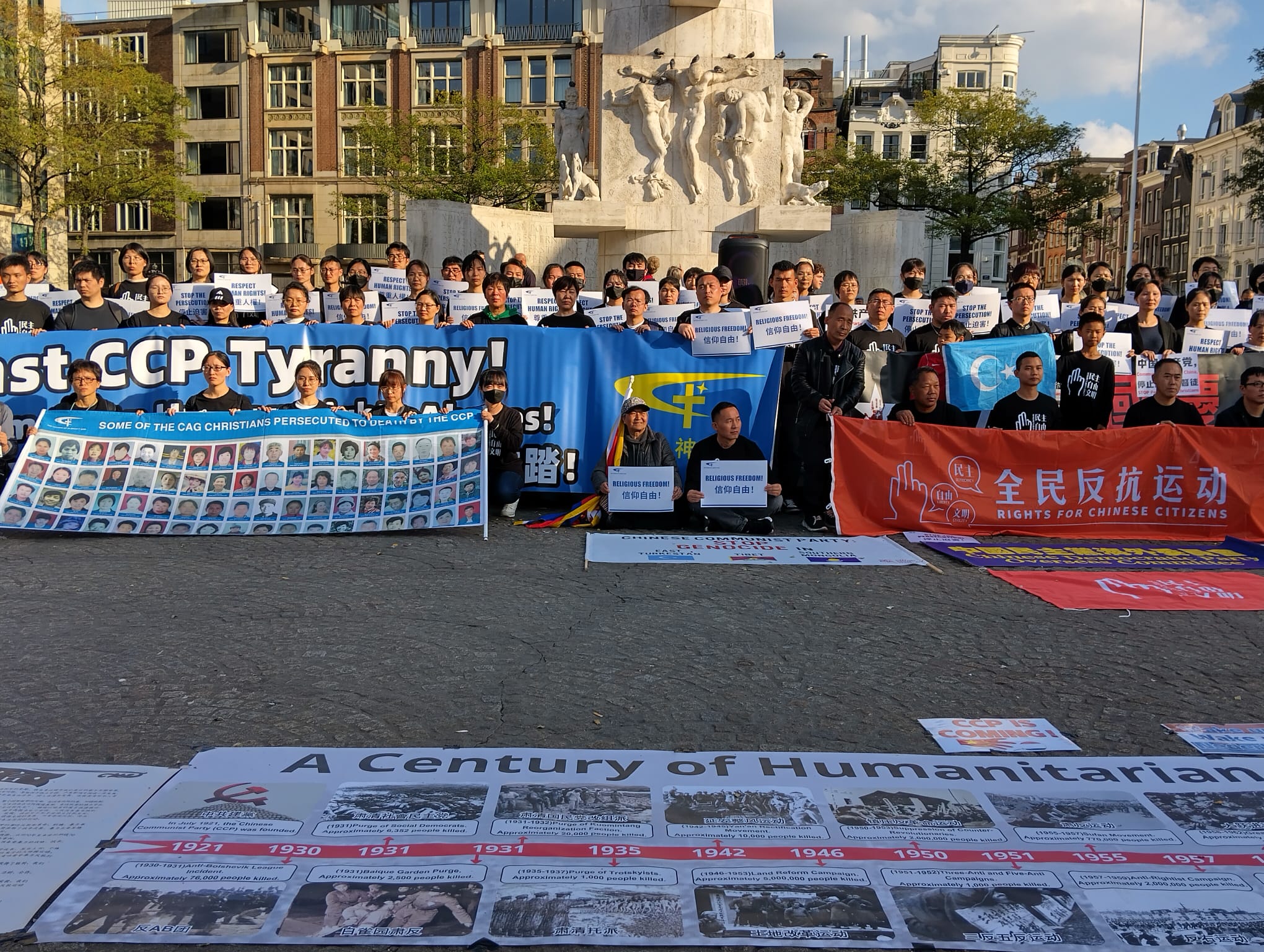Demonstranten op de Dam in Amsterdam houden spandoeken tegen CCP tirannie