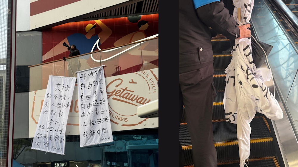 Witte banners met anti-CCP slogans hangen over een straat in het Sanlitun district van Beijing