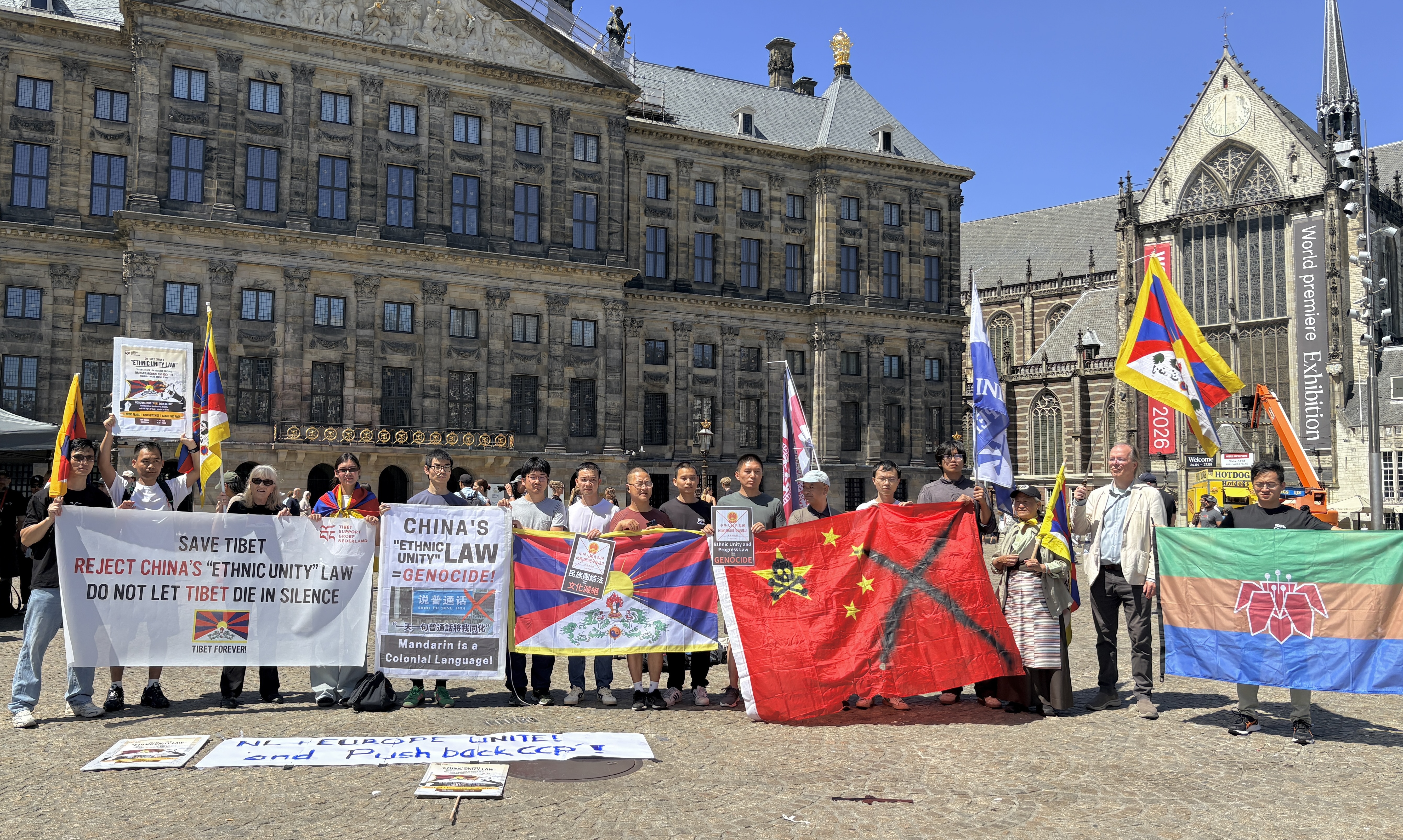 Demonstranten met Tibetaanse, Oeigoerse en andere vlaggen en spandoeken op de Dam in Amsterdam tijdens het protest tegen China's Etnische-Eenheidswet, 1 juli 2026