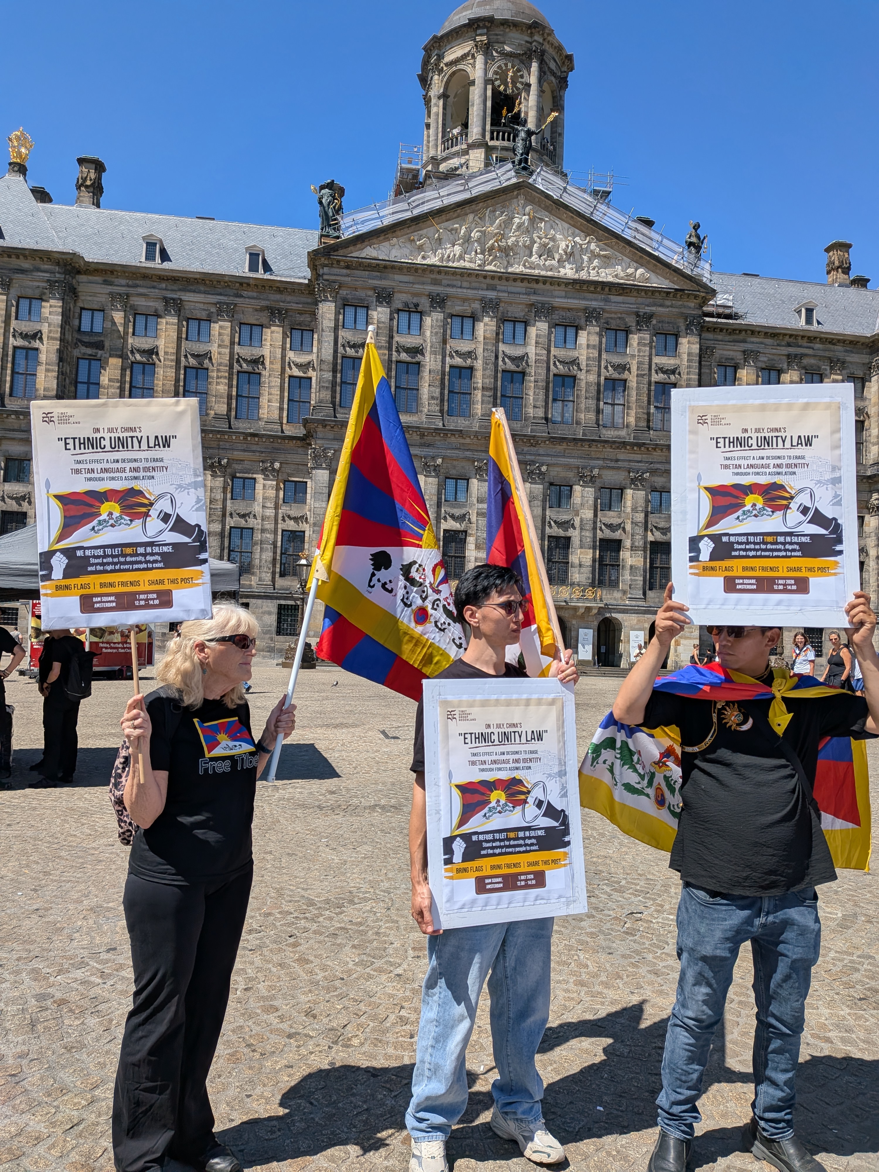 Deelnemers met vlaggen en spandoeken tijdens het protest tegen China's Etnische-Eenheidswet op de Dam in Amsterdam, 1 juli 2026