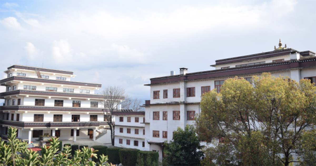 Witte gebouwen in traditionele stijl van het Kathmandu University Centre for Buddhist Studies aan het Rangjung Yeshe Institute, omgeven door bomen