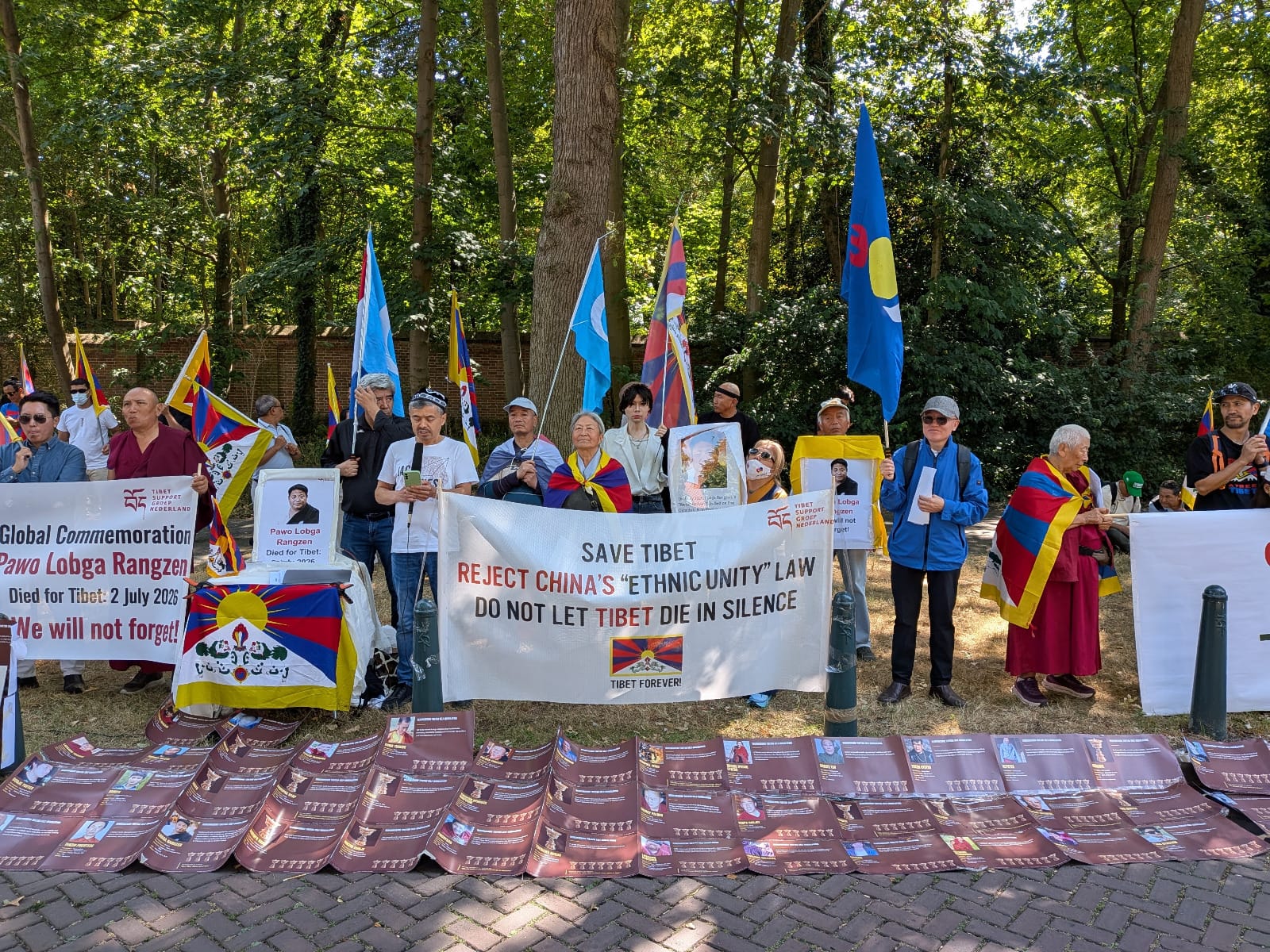 Spandoek met de tekst Save Tibet — Reject China's Ethnic Unity Law, met daarvoor portretten van omgekomen Tibetanen op de stoep