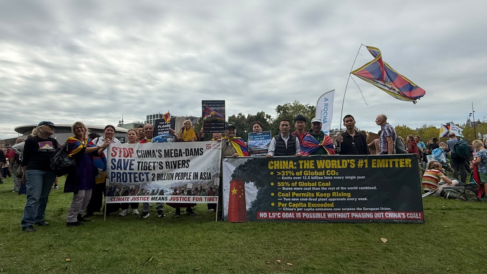 Groepsfoto van TSG-deelnemers, Tibetanen en Chinese mensenrechtenverdedigers met spandoeken en Tibetaanse vlaggen op het Museumplein