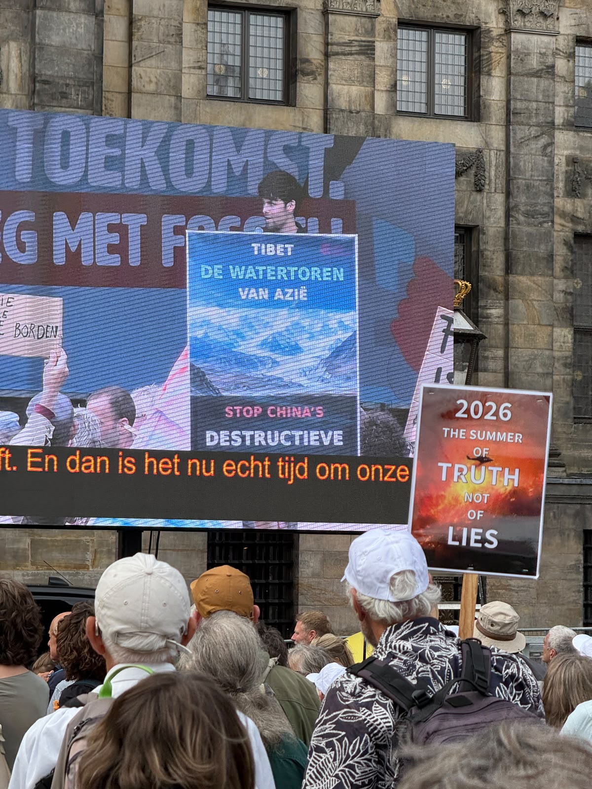 Groot videoscherm op de Dam toont de TSG-poster "Tibet, de watertoren van Azië — stop China's destructieve milieubeleid"