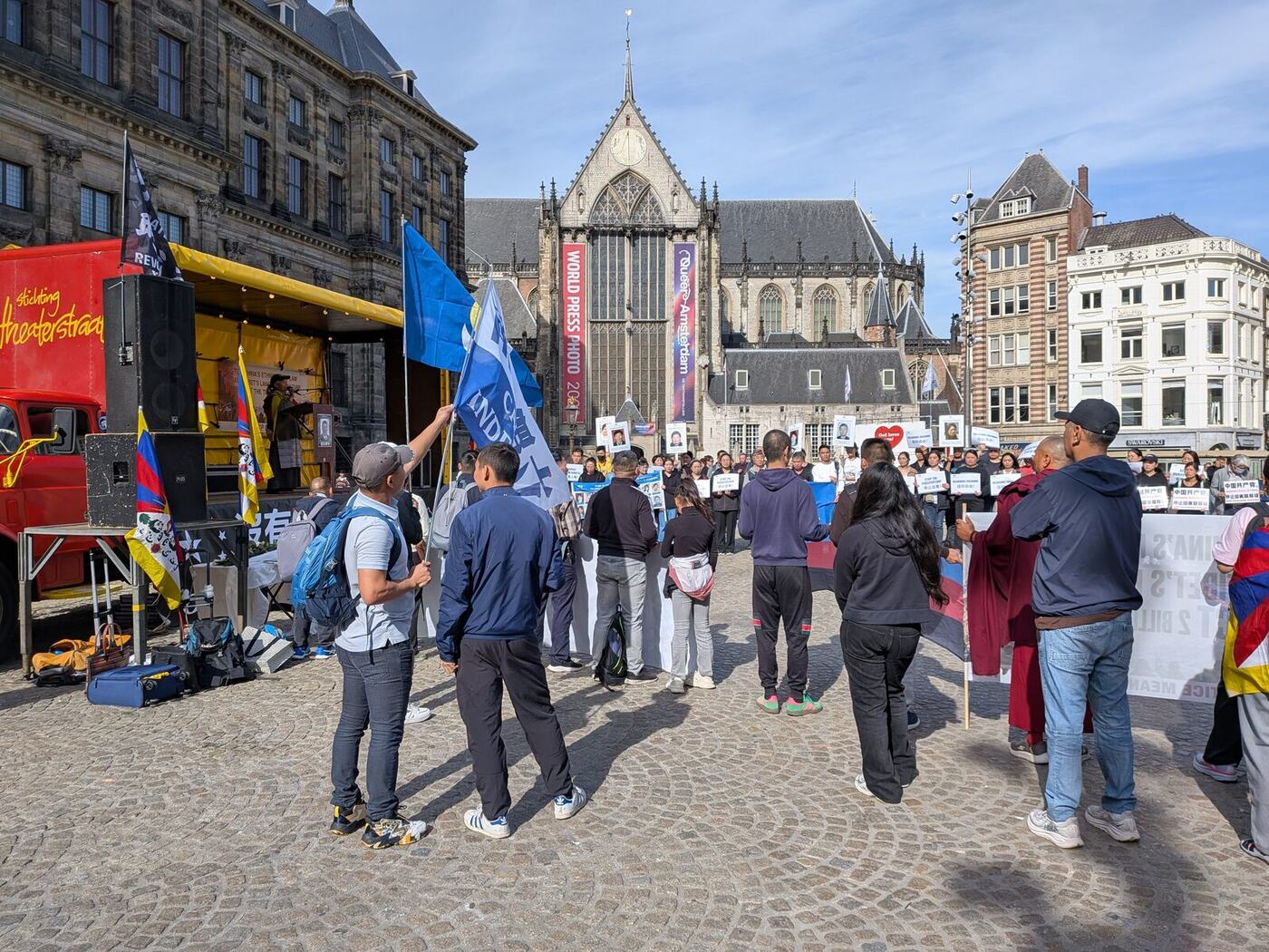 Demonstranten met Tibetaanse vlaggen en spandoeken op de Dam, met de Nieuwe Kerk op de achtergrond