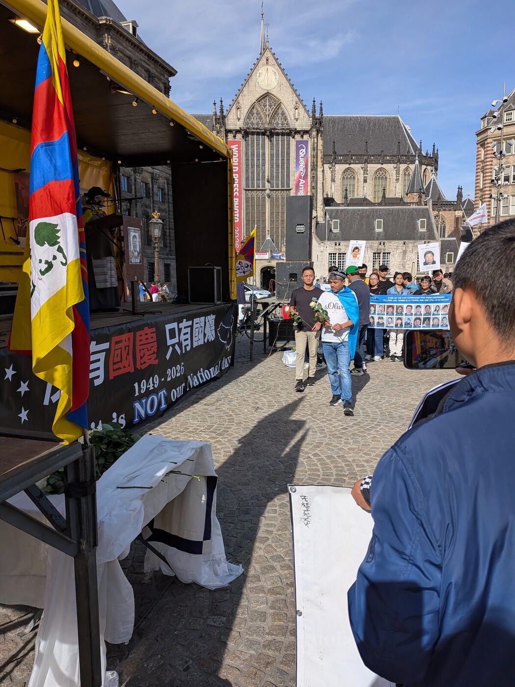 Deelnemers leggen witte rozen neer bij het podium op de Dam
